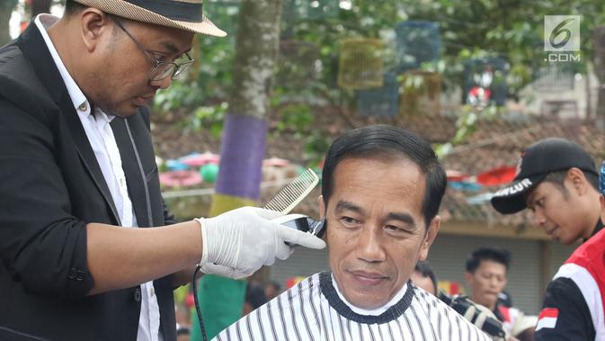 Presiden Joko Widodo saat mengikuti acara cukur rambut massal di Garut, Jawa Barat, Sabtu (19/1). Tak hanya Jokowi, Menteri PUPR Basuki Hadimuljono serta Kepala Sekretariat Presiden Heru Budi Hartono  ikut memangkas rambutnya. (Liputan6.com/Angga Yuniar)