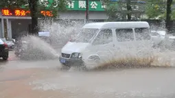 Sebuah mobil menerobos jalan yang tergenang air di Wilayah Pan'an, Kota Jinhua, Provinsi Zhejiang, China timur (4/8/2020). Topan membawa angin berkecepatan 38 meter per detik di dekat pusatnya. (Xinhua/Kong Debin)