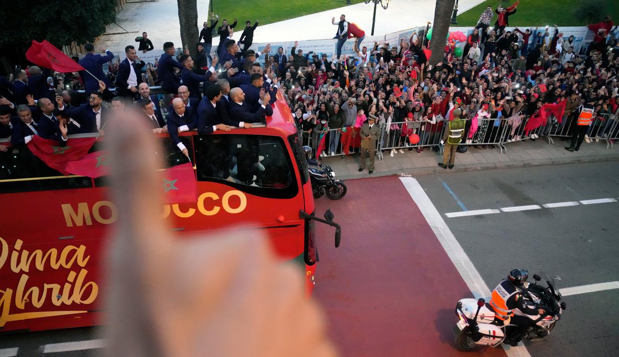 <p>Para pemain Timnas Maroko melakukan selebrasi di atas bus dan melambaikan tangan ke publik saat parade di Rabat , Maroko, 20 Desember 2022. Timnas Maroko mendapat sambutan hangat di negaranya setelah berhasil meraih juara keempat Piala Dunia 2022. (AP Photo/Mosa'ab Elshamy)</p>