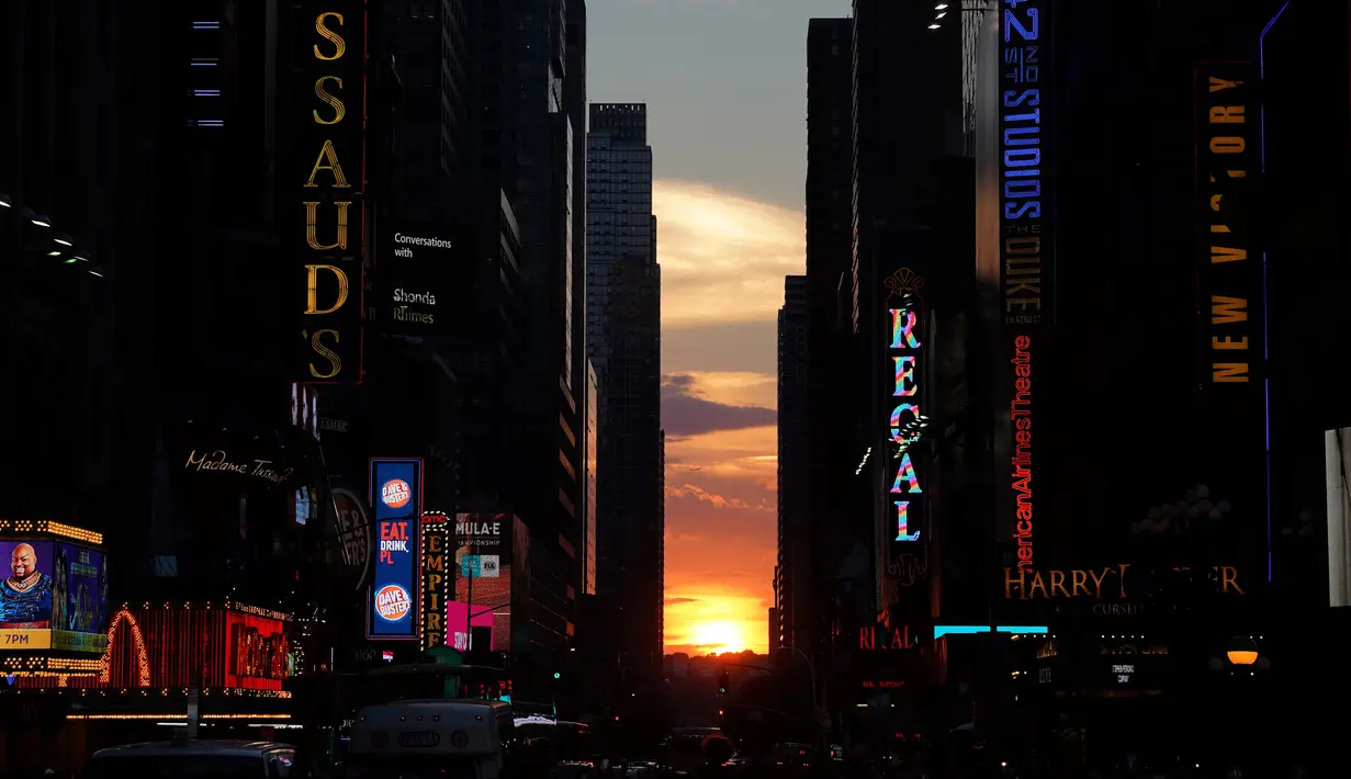 Matahari terbenam di antara pencakar langit ketika fenomena Manhattanhenge di 42nd street di Times Square, New York City, Kamis (12/7). Fenomena manhattanhenge terjadi dimana saat matahari terbenam sejajar dengan jalan. (AFP/TIMOTHY A. CLARY)