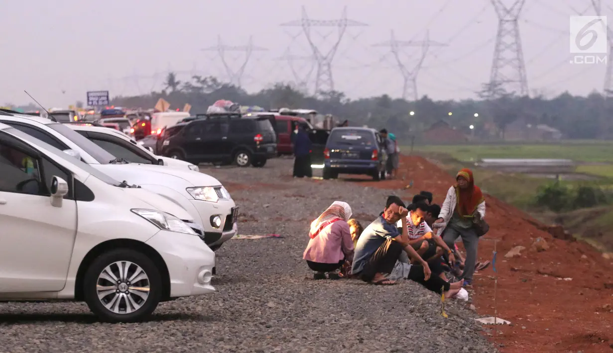 Pemudik beristirahat sambil berbuka puasa di pinggir Tol Fungsional Pemalang-Batang, Jawa Tengah, Minggu (10/6). Sambil berbuka mereka juga mendinginkan kendaraannya. (Liputan6.com/Arya Manggala)