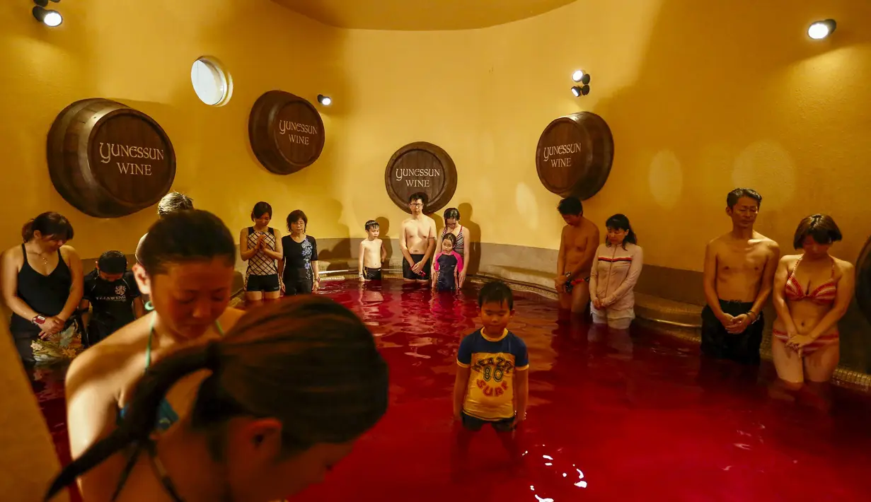 Sejumlah orang berdoa memperingati korban serangan paris di dalam air panas dengan air berwarna anggur di resor spa Hakone Kowaki-en Yunessun saat Beaujolais Nouveau Day di Hakone barat Tokyo,Jepang (19/11). (REUTERS/Thomas Peter)
