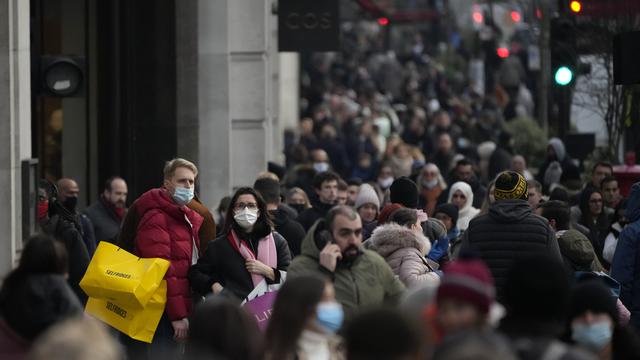 Orang-orang berdiri memegang tas belanja di Regent Street di London, Senin (29/11/2021). Di Inggris, kewajiban mengenakan masker akan berlaku lagi di toko-toko dan transportasi umum mulai Selasa menyusul temuan Covid-19 varian Omicron. (AP Photo/Matt Dunham)