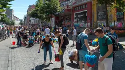 Sejumlah orang membersihkan jalanan di sebuah perumahan setelah aksi protes KTT G20 di Hamburg, Jerman, Minggu (9/7). Dalam aksi tersebut, demonstran nekat membakar mobil, memecahkan kaca jendela dan menjarah sejumlah toko. (Christophe Gateau/dpa/AFP)