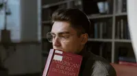 Pria berkacamata membaca kamus di perpustakaan (Liputan6.com/Pexels/tima-miroshnichenko)