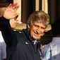 Pelatih Manchester City, Manuel Pellegrini, melambaikan tangan ke arah ribuan suporter yang memadati jalan-jalan untuk menyaksikan parade dua gelar juara "The Citizens" musim 2013/2014, (13/5/2014). (REUTERS/Phil Noble)