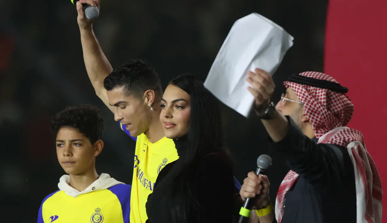<p>Cristiano Ronaldo bersama sang kekasih Georgina Rodriguez dan putranya Cristiano Ronaldo Jr naik panggung saat upacara penyambutan dirinya sebagai pemain baru Al Nassr di Stadion Mrsool Park, di ibu kota Saudi, Riyadh, Selasa (3/1/2023). (Fayez Nureldine / AFP)</p>
