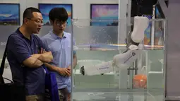 Dua pria melihat robot yang digunakan dalam operasi bawah laut selama China International Robot Show di Shanghai (10/7/2019). Pameran yang menghadirkan robot-robot canggih ini diselenggarakan dari 10 sampai 13 Juli 2019. (AFP Photo/STR)