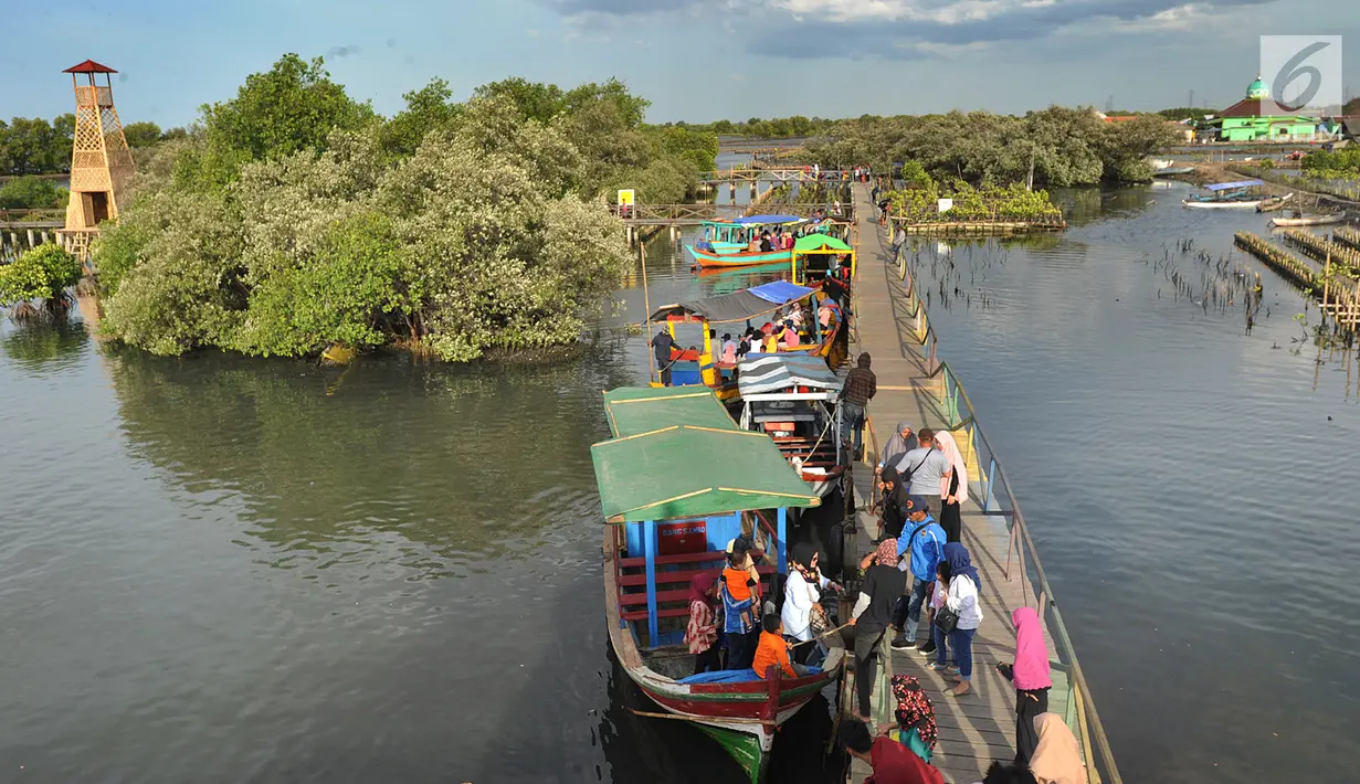 Perahu wisata melintasi kerumunan wisatawan yang berjalan di atas Jembatan Cinta di Wisata Mangrove, Tarumajaya, Bekasi, Minggu (30/12). Wisata tersebut menyajikan hutan mangrove dan makanan khas. (merdeka.com/Arie Basuki)