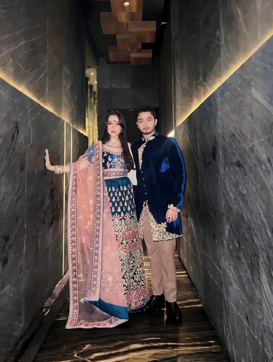 Megan Domani kenakan sari yang nyaris serupa dengan Indah Permatasari berwarna rose gold dan biru metalik. Hadir bersama sang kakak, Bryan Domani, yang tampil gagah dengan busana velvet navy dan celana cokelat [@megandomani1410]