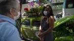 Roberta Machado (kanan) asal Brasil dan pelanggan berbincang di sebelah VW Beetle 1969 miliknya yang diubah menjadi toko bunga keliling di Copacabana, Rio de Janeiro, Rabu (14/10/2020). Perempuan 51 tahun ini mengubah VW kodok untuk bertahan dari krisis akibat pandemi COVID-19. (MAURO PIMENTEL/AFP)