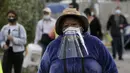 Seorang wanita mengenakan face shield di maskernya bergabung dengan pensiunan untuk disuntik vaksin Covid-19 di luar pusat vaksinasi Social Security Institute di Quito, Ekuador, Kamis (6/5/2021). Para lansia dan pendampingnya menunggu berjam-jam untuk divaksinasi. (AP Photo/Dolores Ochoa)