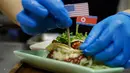 Seorang koki menghias makanan taco bernama El Trumpo dan Rocket Man di sebuah restoran di Singapura, 7 Juni 2018. Makanan itu memanfaatkan momentum pertemuan Donald Trump dan Pemimpin Korea Utara Kim Jong-un di Singapura 12 Juni nanti. (AP/Wong Maye-E)