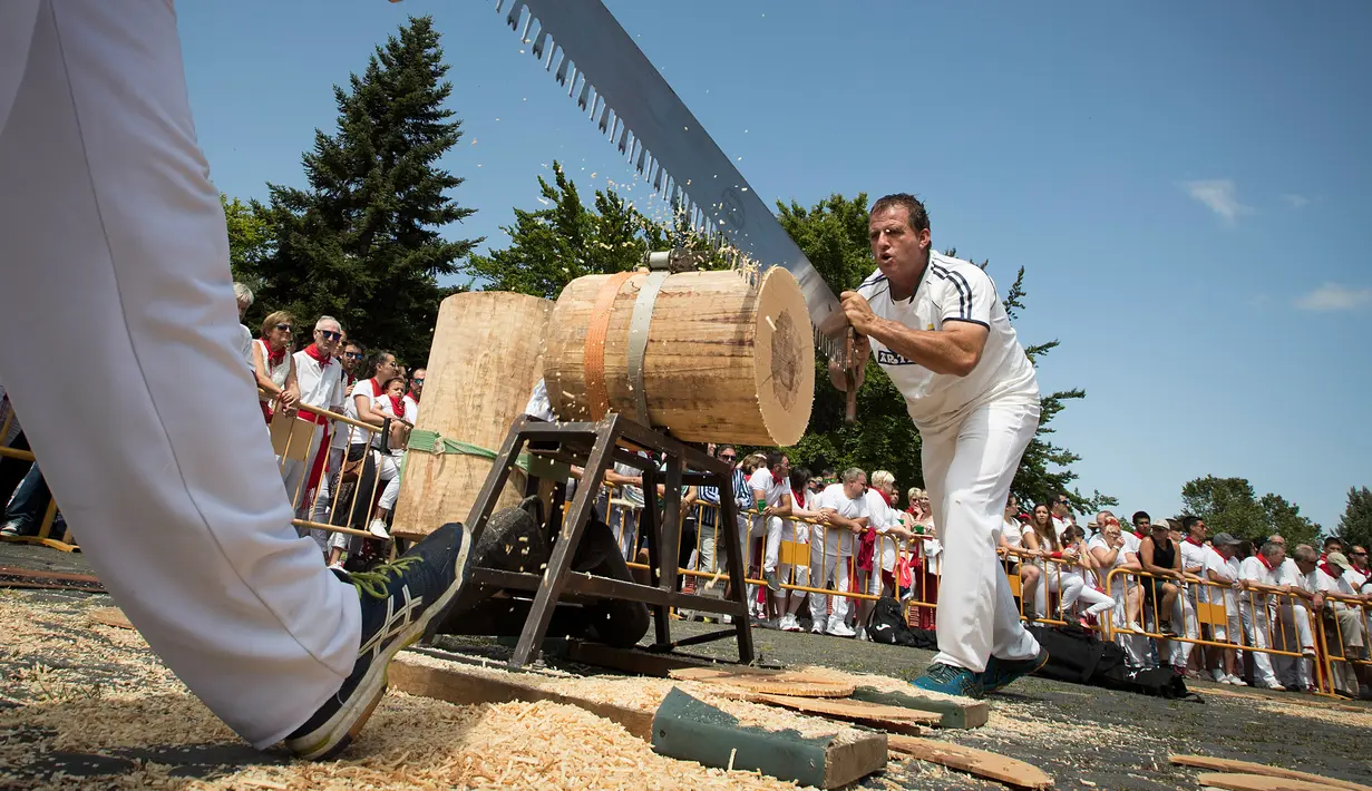 Peserta menggergaji batang pohon dengan "tronza", gergaji tradisional daerah Basque, pada hari ketiga festival San Fermin di Pamplona, Spanyol, Senin (8/7/2019). Festival San Fermin menghadirkan beberapa olahraga pedesaan Basque seperti menggergaji dan memotong pohon dengan kapak. (JAIME REINA/AFP)