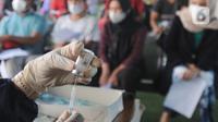Vaksinator menyiapkan vaksin dosis ketiga untuk warga dan pedagang pasar di kolong flyover Ciputat, Tangerang Selatan, Sabtu (2/4/2022). Vaksinasi booster tersebut diselenggarakan oleh Polsek Ciputat Timur dan Polres Tangerang Selatan. (merdeka.com/Arie Basuki)