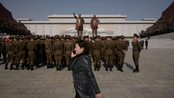 Seorang wanita berbicara di ponsel ketika tentara Tentara Rakyat Korea Utara tengah bersiap-siap (AFP)