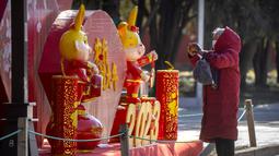 Seorang wanita mengambil foto hiasan untuk Tahun Baru Imlek di sebuah taman umum di Beijing, Jumat, 20 Januari 2023. Tahun Kelinci secara resmi dimulai pada 22 Januari. (AP Photo/Mark Schiefelbein)