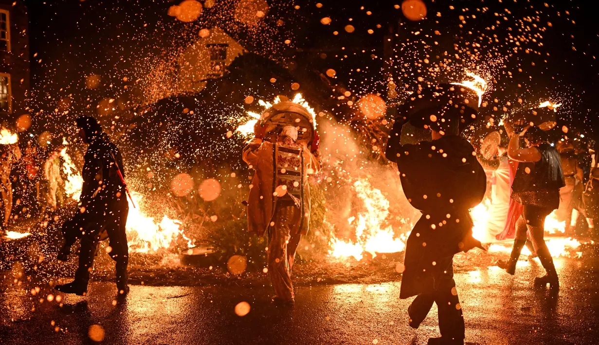Para pria meletakkan tong-tong mereka yang menyala di atas api di akhir prosesi mereka melalui jalan-jalan selama festival tahunan Allendale Tar Barrel di Allendale, Inggris utara, pada malam hari antara tanggal 31 Desember 2024 dan 1 Januari 2025. (Oli SCARFF/AFP)