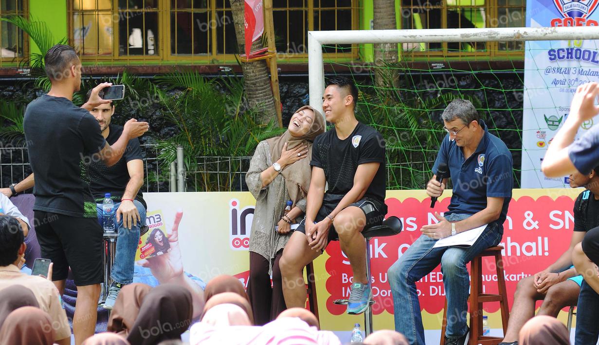 Raphael Maitimo memberikan hadiah kepada guru yang ingin berfoto dengan Ryuji Utomo dalam acara Arema Goes to School. Sabtu (30/4/2016). (Bola.com/Iwan Setiawan)