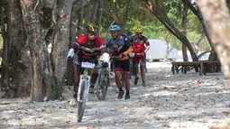 Para pebalap melintasi trek berpasir Mountain Bike Cross Country Marathon pada Festival Pesona Tanjung Lesung 2017 di Tanjung Lesung, Banten (23/9/2017). MTB XCM tersebut menempuh jarak 48 km. (Bola.com/Nicklas Hanoatubun)