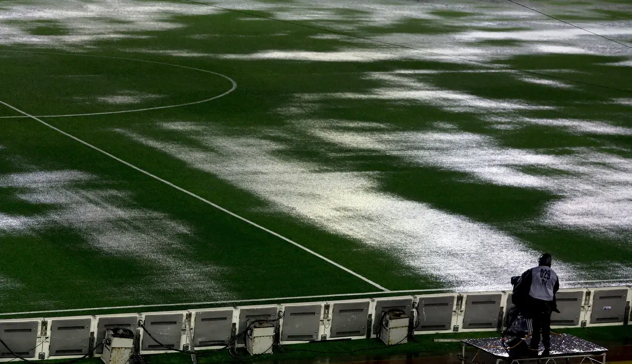 Seorang kamerawan saat berada dipinggir lapangan tergenang air akibat hujan lebat di stadion Monumental, Argentina, Jumat (13/11/2015). Karena cuaca buruk Pertandingan antara Argentina dan Brasil mengalami pengunduran. (REUTERS/Marcos Brindicci)