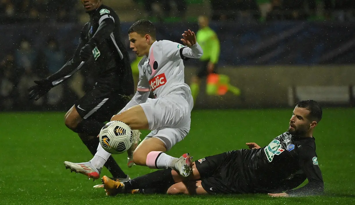Gelandang Paris Saint-Germain (PSG) Ismael Gharbi (tengah) ditekel oleh pemain klub divisi empat, Vannes OC dalam babak 32 besar Piala Prancis di Stade de la Rabine, Selasa (4/1/2021) dini hari WIB. PSG menang 4-0 lewat hattrick Kylian Mbappe. (LOIC VENANCE/AFP)