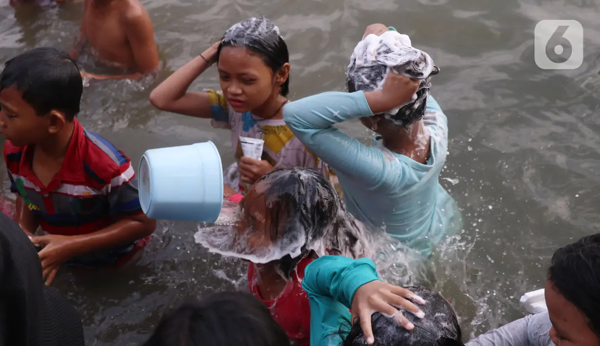 Anak-anak saat dikeramas di bantaran sungai Cisadane di kawasan Babakan, Kota Tangerang, Jumat (1/4/2022). Keramas bersama merupakan tradisi warga yang berada dikawasan tersebur sebagai simbol membersihkan diri untuk menyambut bulan Ramadhan. (Liputan6.com/Angga Yuniar)