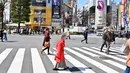 Pejalan kaki melintasi persimpangan pejalan kaki yang terkenal di distrik Shibuya, Tokyo pada 20 Maret 2019. Persimpangan jalan ini menjadi salah satu persimpangan terbesar dan tersibuk di dunia. (Photo by CHARLY TRIBALLEAU / AFP)