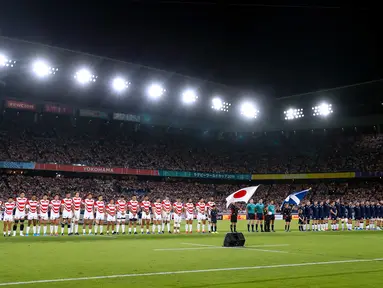 Pemain rugby Jepang dan Skotlandia berdoa bersama selama satu menit untuk korban Topan Hagibis sebelum Pertandingan Pool A Piala Dunia Rugbi 2019 di Stadion Internasional Yokohama (13/10/2019). (AFP Photo/Odd Andersen)