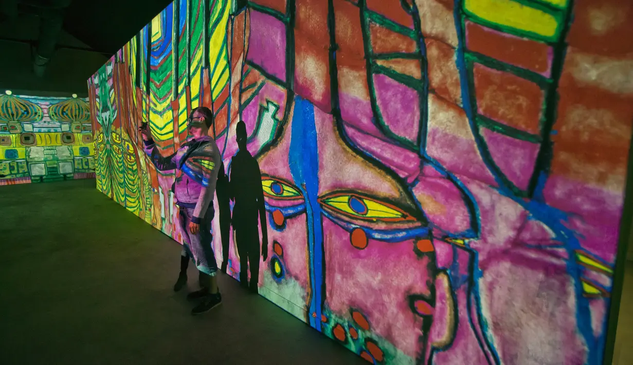 Pengunjung berswafoto dengan karya seniman Austria, Friendensreich Hundertwasser dalam pameran seni proyeksi di galeri l'Atelier des Lumieres di Paris, Prancis (24/4). (AP/Michel Euler)