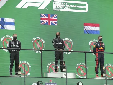 Pembalap Mercedes Lewis Hamilton (tengah) berdiri di podium bersama pembalap Mercedes Valtteri Bottas dan pembalap Red Bull Max Verstappen selama Formula 1 GP Portugaldi Algarve International Sirkuit di Portimao, Portugal, Minggu (25/10/2020).  (Jose Sena Goulao, Pool via AP)