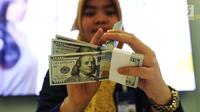 Pekerja bank menghitung uang dollar AS di Jakarta, Jumat (20/10). Pagi ini, Rupiah dibuka di Rp 13.509 per USD atau menguat tipis dibanding penutupan perdagangan sebelumnya di Rp 13.515 per USD. (Liputan6.com/Angga Yuniar)