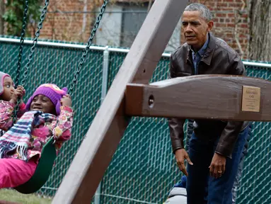 Presiden AS Barack Obama bermain ayunan dengan anak-anak dari sebuah tempat penampungan di Washington DC, AS, Selasa (16/1). Obama menyumbangkan wahana bermain milik kedua putrinya yang dipasang di luar Oval Office. (AFP PHOTO / YURI GRIPAS)