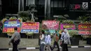 Warga melintas dekat karangan bunga berisi dukungan pada KPK di halaman Gedung KPK, Jakarta, Senin (20/11). Karangan bunga tersebut sebagai bentuk dukungan masyarakat kepada KPK terhadap pemberantasan kasus korupsi e-KTP. (Liputan6.com/Faizal Fanani)