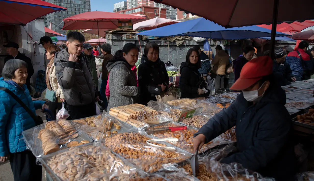 Sejumlah orang mengantre saat berbelanja kue di pasar di Beijing (20/11).  (AFP Photo/Nicolas Asfouri)