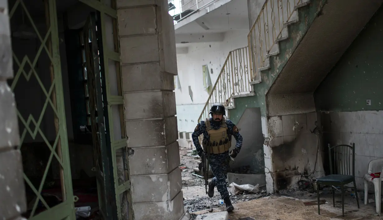 Polisi Irak berlari mencari perlindungan di dalam gedung saat bertempur melawan militan ISIS di barat Mosul, Irak, 16 Maret 2017. (AP Photo/Felipe Dana)