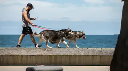 Seorang pria berjoging bersama anjing-anjingnya di Pantai St Kilda di Melbourne, Australia, pada 9 Desember 2020. Kehidupan pantai kembali terlihat setelah Melbourne mengakhiri masa pemberlakuan lockdown COVID-19 pada November lalu, yang berlangsung selama hampir empat bulan. (Xinhua/Hu Jingchen)