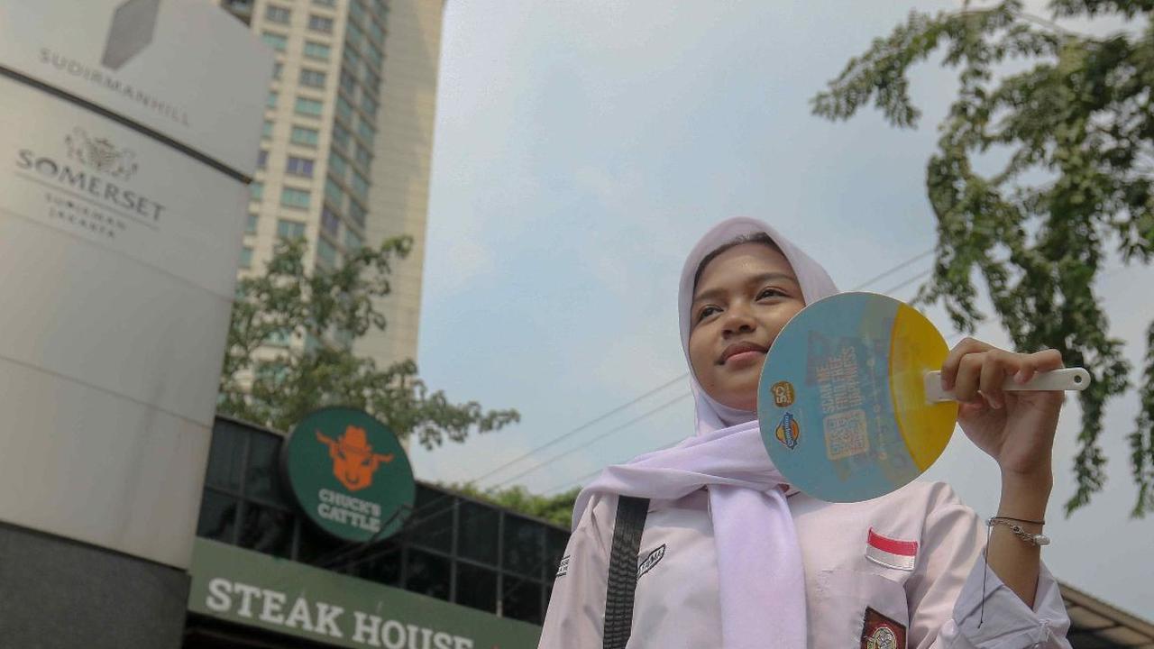 Pelajar menggunakan kipas saat menunggu tranportasi umum di kawasan Bendungan Hilir, Jakarta, Rabu (8/5/2024). Dalam beberapa hari terakhir suaca panas melanda sejumlah wilayah di Indonesia, termasuk Jakarta. Foto: Liputan6.com/Herman Zakharia<br>