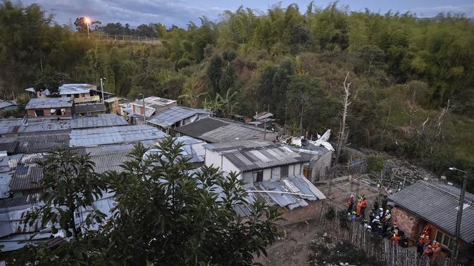 Tim penyelamat berada di lokasi jatuhnya sebuah pesawat kecil di tengah-tengah rumah penduduk di Popayan, Kolombia, Minggu (15/9/2019). Pemadam kebakaran mengatakan tiga orang luka parah, salah satunya adalah seorang anak yang merupakan warga setempat. (Luis ROBAYO / AFP)