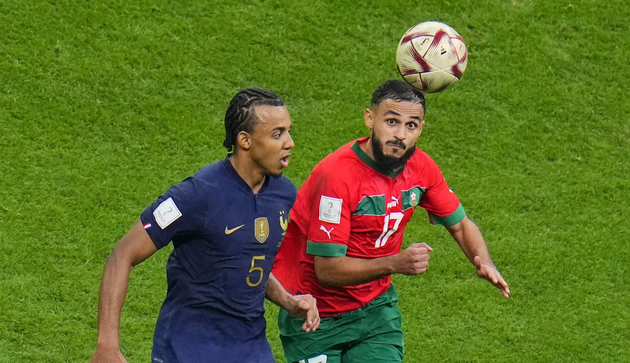 Gelandang Maroko, Sofiane Boufal berebut bola dengan bek Prancis, Jules Kounde pada pertandingan semifinal Piala Dunia 2022 di Maroko di Stadion Al Bayt di Al Khor, Qatar, Kamis (15/12/2022). Prancis menang atas Maroko dengan skor 2-0.  (AP Photo/Hassan Ammar)