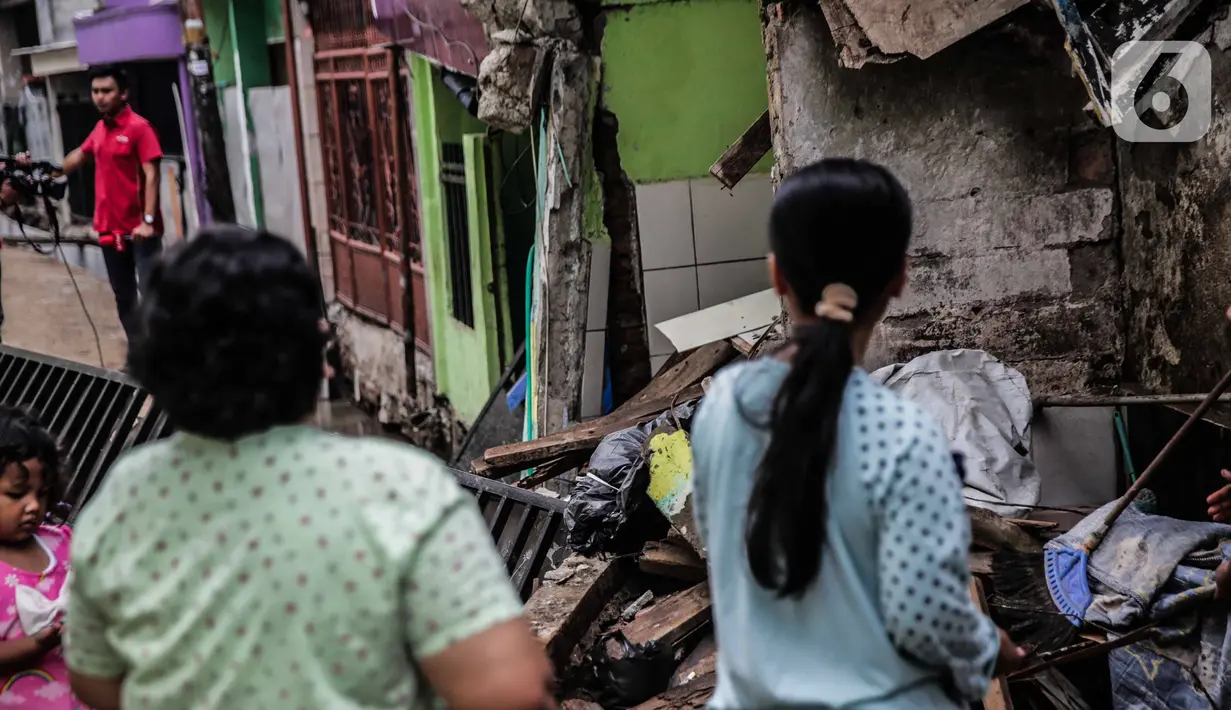 Warga melihat rumah yang roboh akibat pembuatan saluran air di Jalan Kayu Manis IX, Matraman, Jakarta Timur, Senin (16/12/2019). Pelaksana pembangunan saluran air akan bertanggung jawab memperbaiki rumah yang telah lapuk fondasinya tersebut mulai Senin. (Liputan6.com/Faizal Fanani)