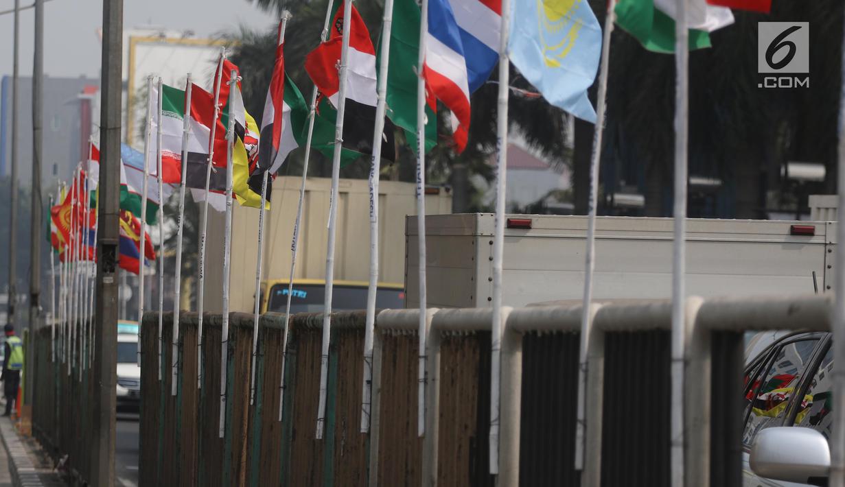 Deretan bendera negara-negara peserta Asian Games 2018 yang diikat di tiang bambu di pagar pembatas Jalan Pluit Selatan Raya, Jakarta, Kamis (19/7). Pemasangan bendera itu sempat menuai kritikan warganet di media sosial. (Liputan6.com/Arya Manggala)