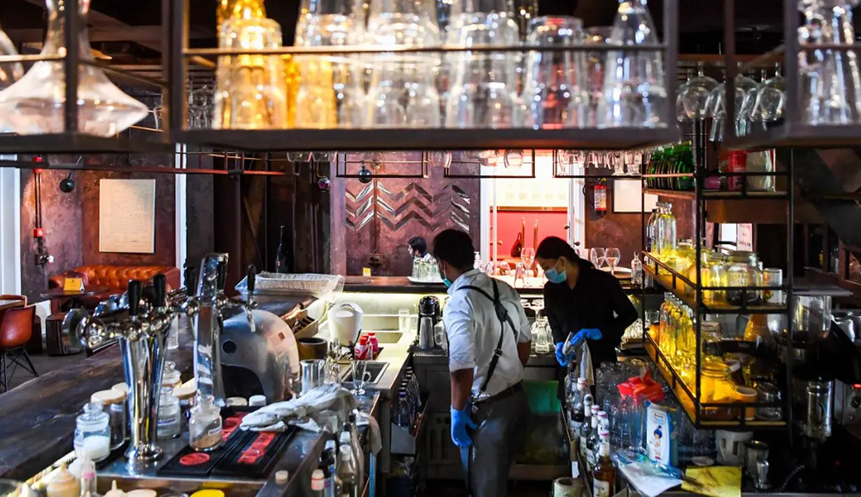 Bartender Gagan (kiri) dan seorang pelayan membersihkan bar jelang pembukaan kembali di New Delhi, 8 September 2020. Setelah sebelumnya ditutup karena pandemi COVID-19, mulai 9 September 2020 New Delhi mengizinkan bar kembali buka dengan kapasitas tempat duduk 50 persen. (Prakash SINGH/AFP)