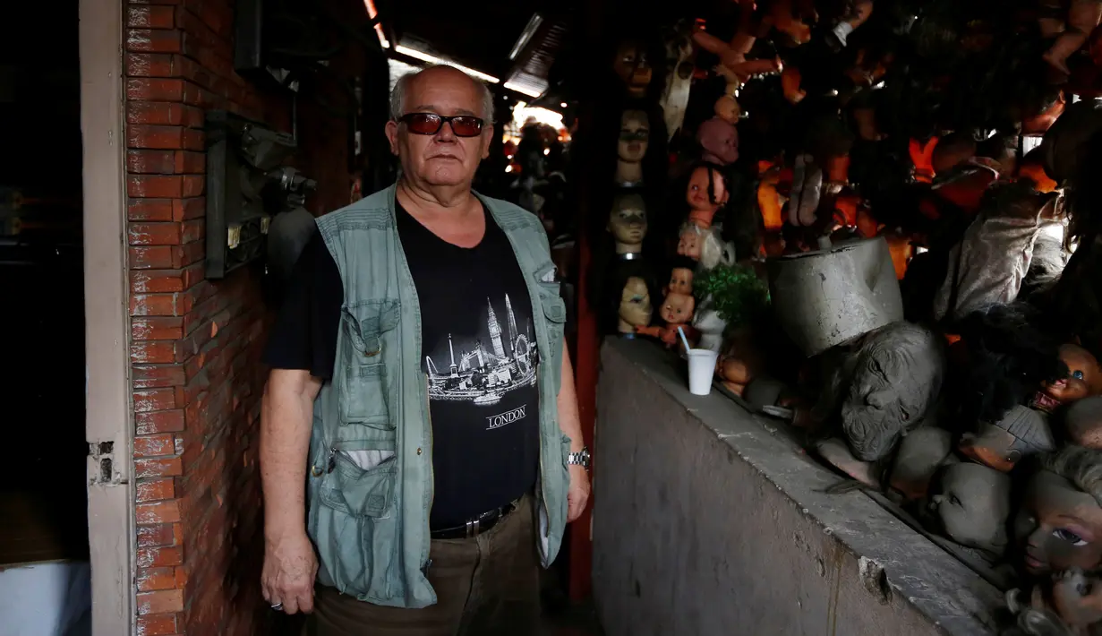 Seorang kolektor bernama Etanis Gonzalez berpose di samping koleksi boneka seram dan menakutkan yang dipajang di balkon rumahnya, di Caracas, Venezuela, 16 Juli 2016. (REUTERS/Carlos JASSO)
