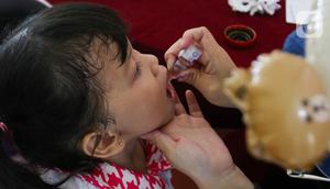 Petugas memberikan vaksin polio tetes kepada seorang anak saat berlangsungnya pekan imuniasasi nasional di RPTRA Kenanga, Cideng, Jakarta, Selasa (23/7/2024). (Liputan6.com/Herman Zakharia)
