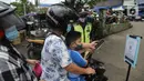 Pengendara motor memindai "barcode" melalui aplikasi PeduliLindungi sebelum memasuki Pasar Anyar di Kota Tangerang, Selasa (26/10/2021). PD Pasar Kota Tangerang memberlakukan penerapan aplikasi PeduliLindungi di dua pasar tradisional, yakni Pasar Anyar dan Pasar Poris. (Liputan6.com/Angga Yuniar)