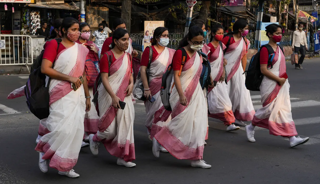 Sekelompok siswa India yang mengenakan masker kembali dari sekolah mereka di Kolkata, 3 Maret 2022. Para ahli optimis bahwa lonjakan omicron, yang membawa tingkat kematian yang relatif rendah, telah memperkuat kekebalan dari vaksin, yang tersebar luas di kawasan tersebut. (AP Photo/Bikas Das)