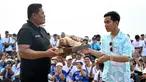 Calon Wakil Presiden nomor urut 2 Gibran Rakabuming Raka (kanan) menerima ukiran penyu saat rapat umum kampanyenya di pantai Sanur, Bali pada 27 Januari 2024. (SONNY TUMBELAKA/AFP)