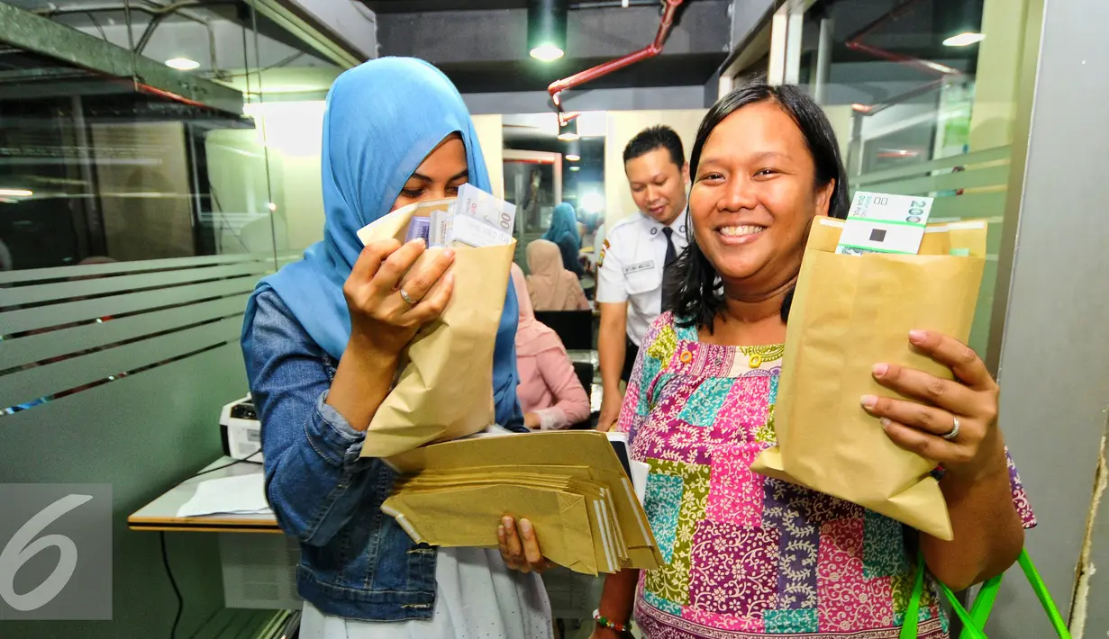  Sejumlah karyawan memperlihatkan uang hasil penukaran uang persiapan Lebaran, Jakarta, Rabu (8/7/2015). BI bersama BTN menggelar layanan penukaran uang bagi karyawan di kantor SCTV Tower. (Liputan6.com/Yoppy Renato)