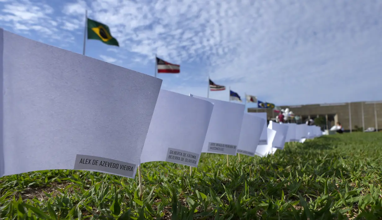 Nama-nama yang meninggal karena COVID-19 menutupi bendera putih sebagai bagian dari protes kebijakan kesehatan pemerintah di luar Kongres Nasional, Brasilia, Jumat (15/10/2021). Sebanyak 600 bendera, masing-masing dengan nama seseorang, mewakili 600.000 total korban meninggal (AP Photo/Eraldo Peres)